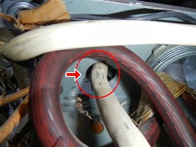 Romex cables entering an electrical panel without connectors, red circle and arrow marking the open knockout.