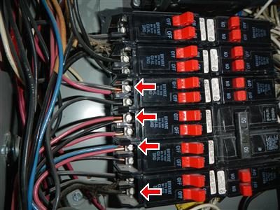 Row of Bryant circuit breakers inside an electrical panel with four red arrows pointing at terminals holding two wires each.