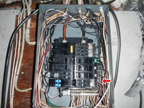 Open electrical panel with breakers and many conductors, red arrow at the lower right breaker.