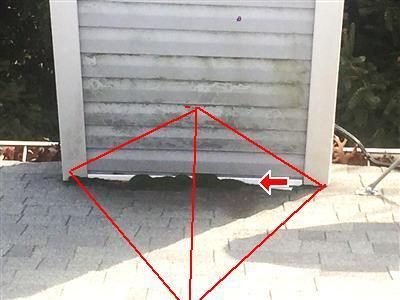 Base of a vinyl-sided chimney on an asphalt roof with red lines marking a cricket shape and an arrow at the moss.