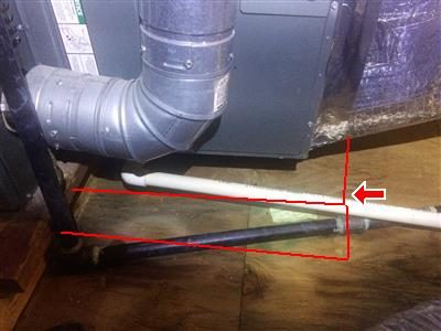 Air handler ductwork and a drain line above a plywood attic floor, red outline and arrow at the drain.