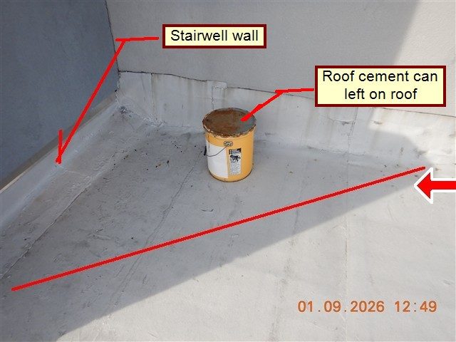 White flat roof beside a stairwell wall with a red diagonal line, a large red arrow, and labels reading stairwell wall and roof cement can left on roof.