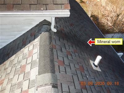 Asphalt shingle roof at a ridge and valley with a red arrow labelled 