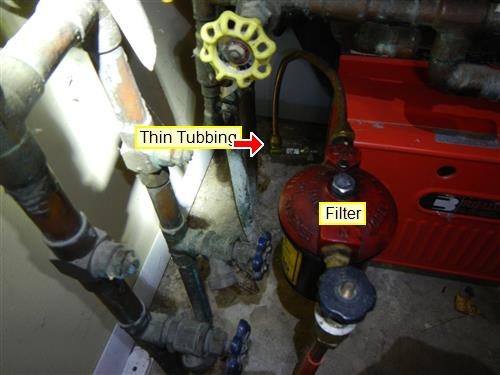 Red oil filter canister beside a burner, labelled 