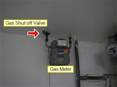 Gas meter mounted high on a basement wall with report labels Gas Shut off Valve and Gas Meter.