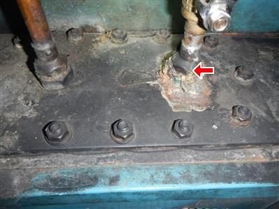 Corroded green-white fitting on top of a boiler jacket where a pipe enters, marked with a red arrow.