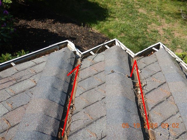 Two shingle roof hip valleys filled with twigs and leaf debris above a gutter, each traced with a red line.