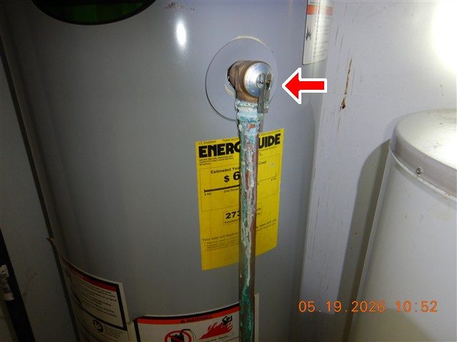Water heater TPR valve with a green-corroded discharge pipe running down the tank, marked with a red arrow.