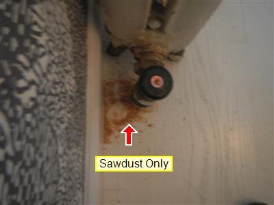 Base of a radiator valve with reddish deposit on the floor, labeled Sawdust Only