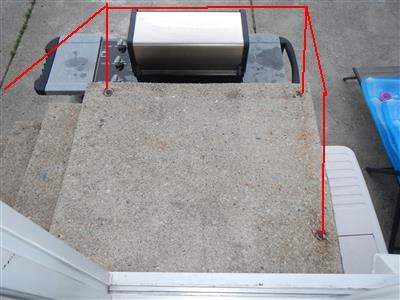Raised concrete platform with anchor bolts at its edges and red markup lines drawn where a railing would stand