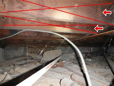 Bare floor joists above a dirt crawl space floor with pipes and a flexible duct, marked with red lines and arrows.
