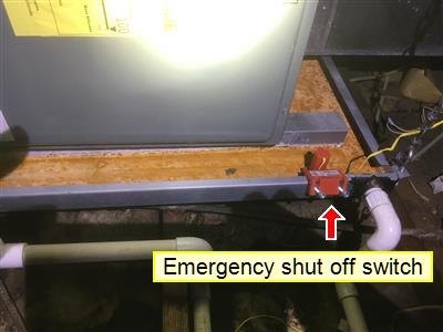 Red emergency shut-off switch mounted beside heating equipment, marked with a red arrow and yellow label