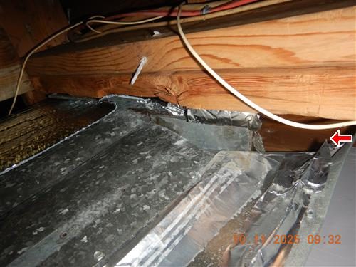 Galvanised steel ductwork under floor joists with loose foil tape at a joint, red arrow at the gap.