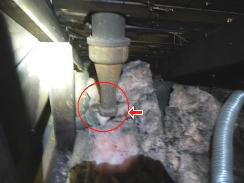 Cast iron plumbing vent stack in an attic ending above pink insulation, with a red circle and arrow at the gap.