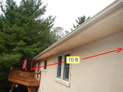 Rear of a stucco house with a long gutter run and a wood deck, marked with a red 70 ft measurement line.
