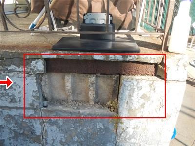 Concrete block side of a rear deck with a cracked and crumbling section outlined in a red box.