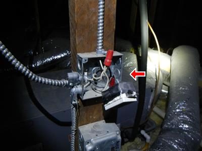 Metal outlet box on an attic post with its cover missing and wires and the receptacle hanging out, marked with a red arrow.