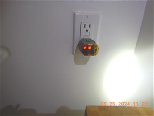 Wall outlet with a plug-in circuit tester showing two red lights.