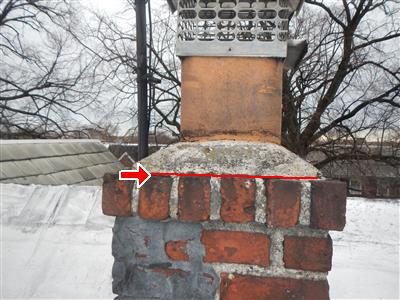 Brick chimney with a cement cap and clay pot, with a red line and arrow along the cracked cap.