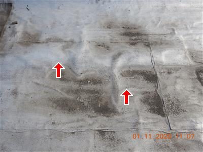 Silver-coated flat roof with raised bubbles and dark staining, marked with two red arrows.