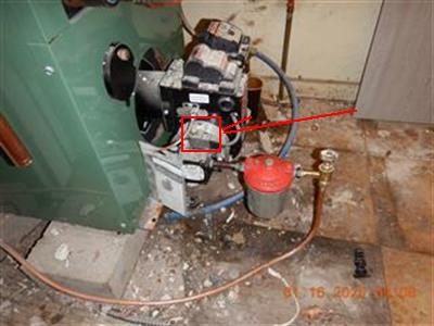 Oil burner on a green boiler with a red fuel filter and copper lines, red box around the solenoid.